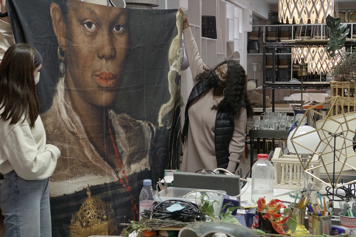 Vom Glück des Findens. Cleo (Thelma Buabeng, Mitte) entdeckt das Porträt »African Woman Holding a Clock« als Aufdruck auf einem Duschvorhang