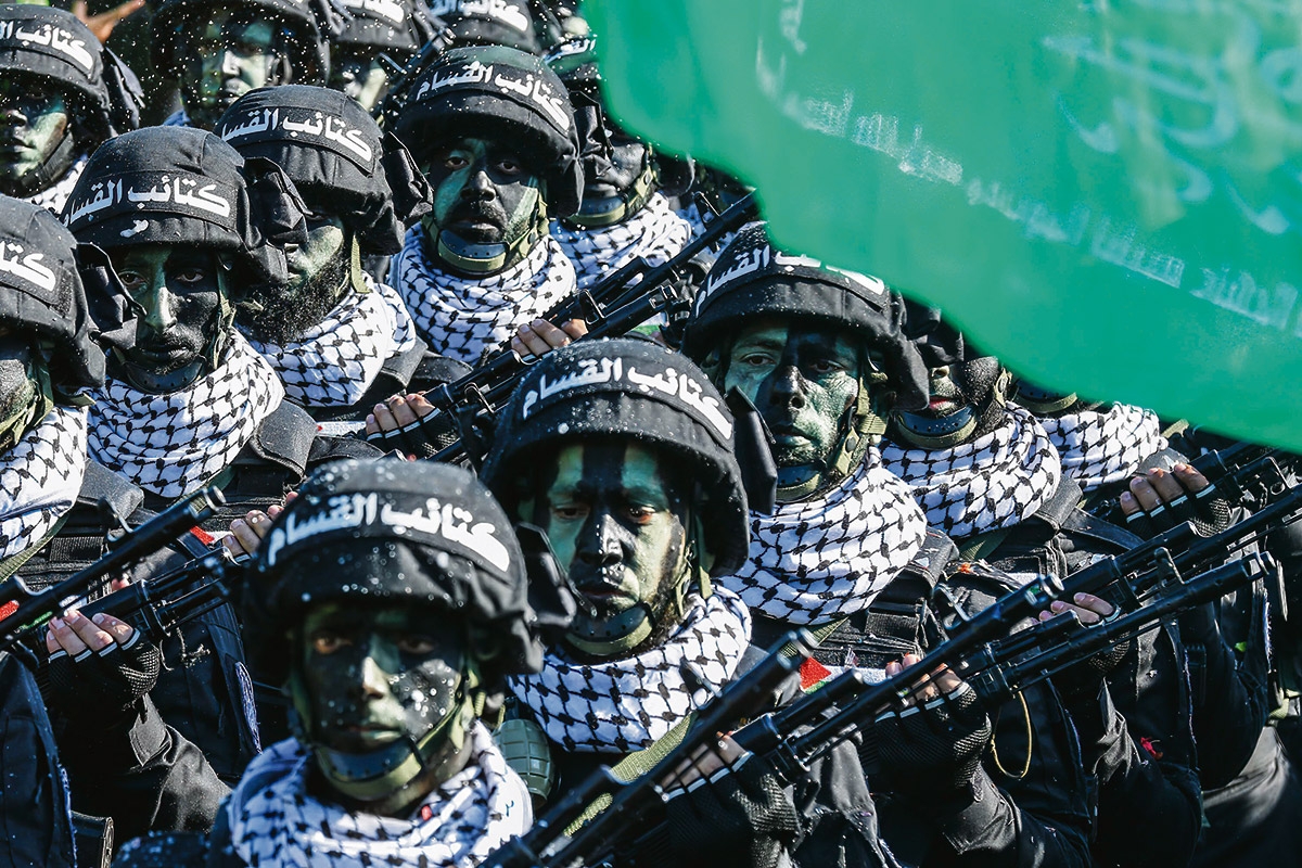 Kämpfer der Hamas in Tarnkleidung, mit Kufiya und »Qassam-Brigaden«, dem offiziellen Namen ihrer Terrororganisation, auf dem Helm marschieren während einer Kundgebung
