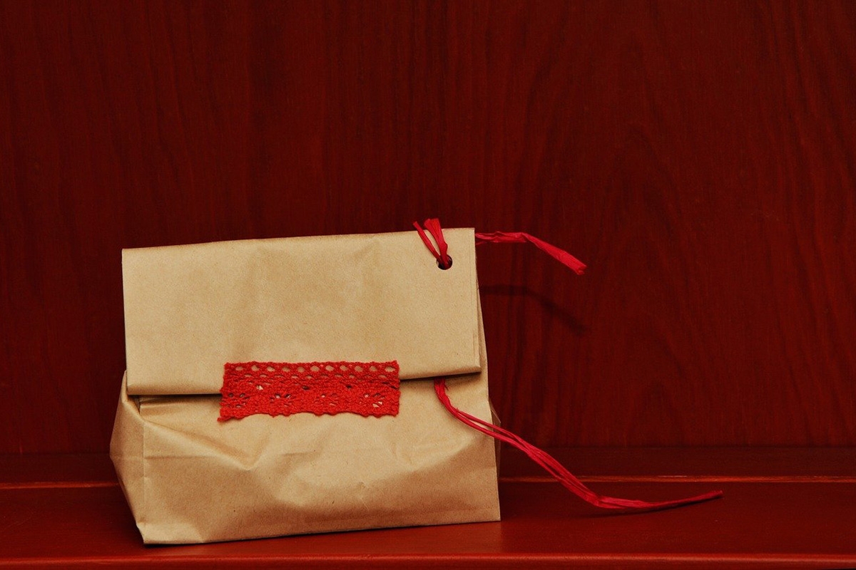 Ein profisorisch in eine Tüte mit rotem Faden und Klebeband verpacktes Geschenk