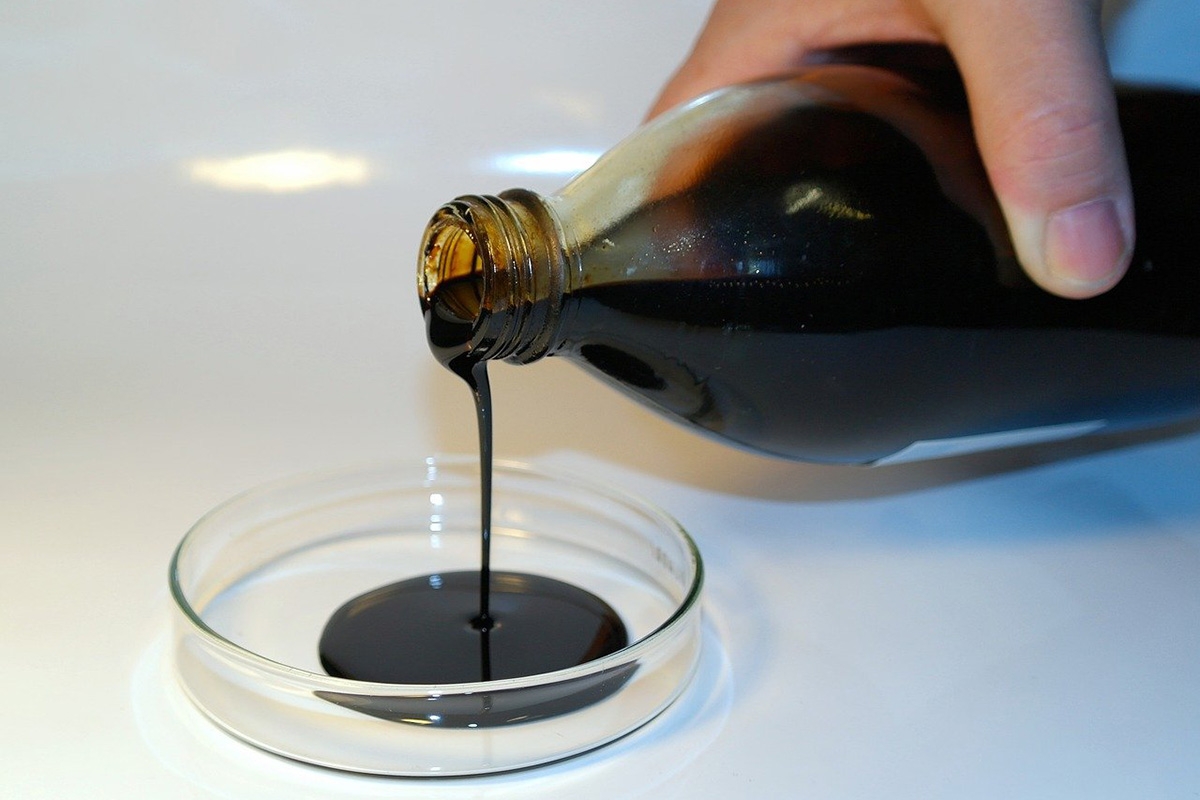 Eine braune zähflüssige Substanz wird aus einer Glasflasche in ein Schälchen gegossen