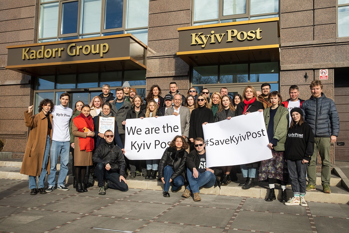Gruppenfoto von Mitarbeitenden der Kyiv Post mit Schildern: "We are the Kyiv Post" und "Save the Kyiv Post"