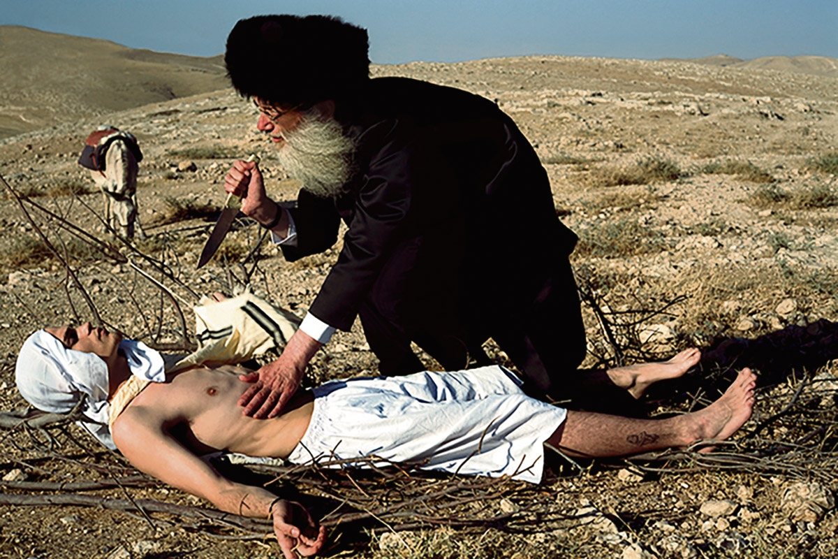 Ein Mann mit Turban sticht auf einen am Boden Liegenden ein