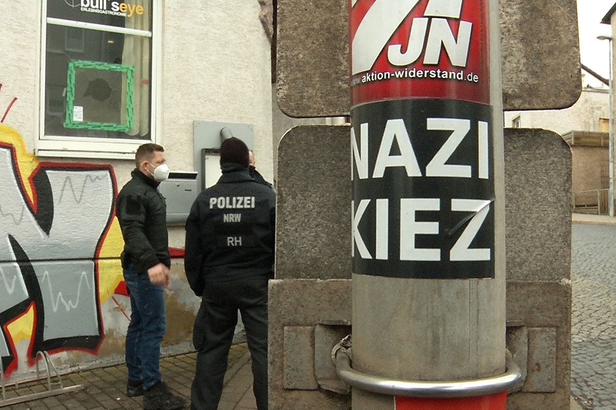 Polizisten stehen vor der Gaststätte "Bull's Eye". An einem Pfahl ist ein Aufkleber mit der Aufschrift Nazi Kiez zu sehen.