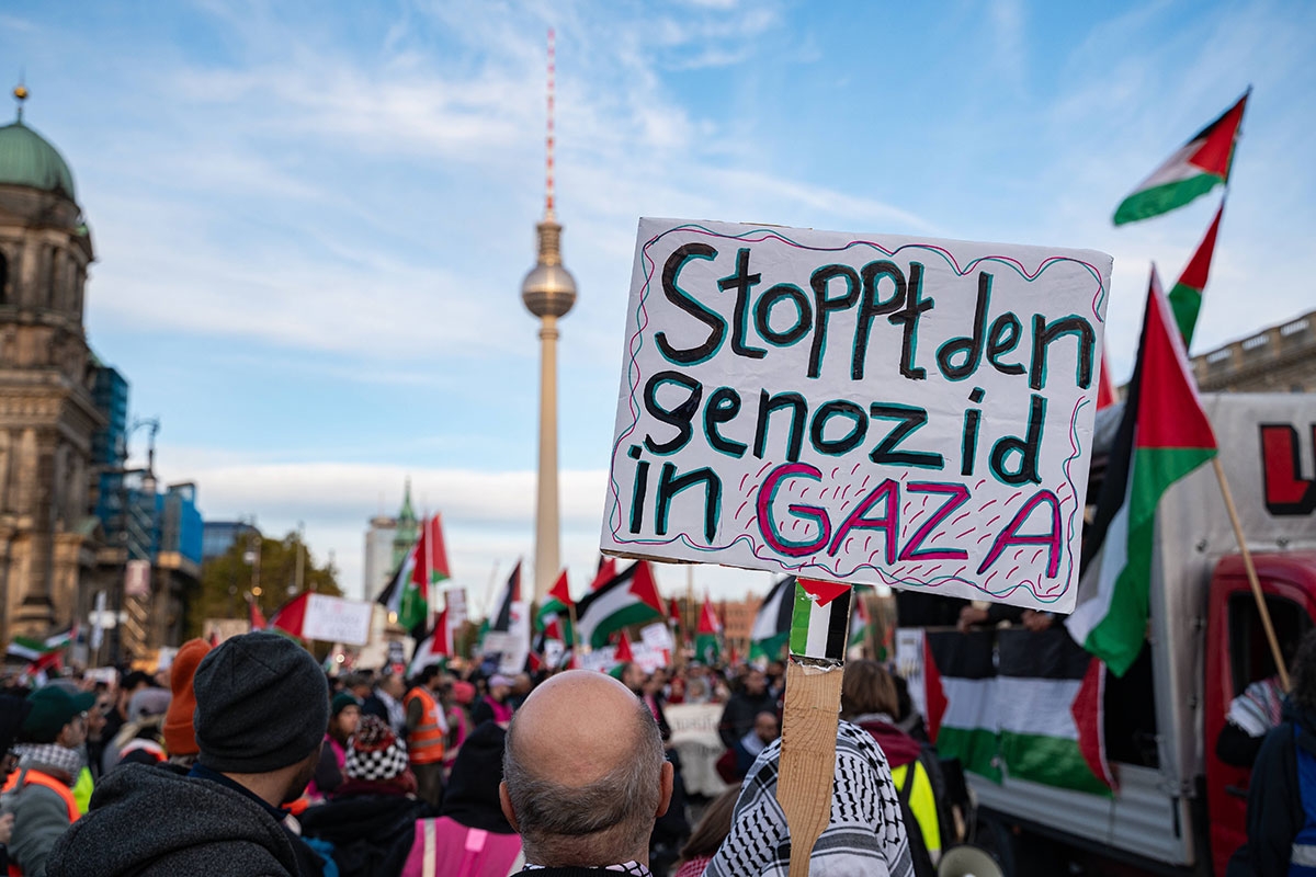 Einer der Teilnehmer haelt ein Schild auf dem steht: "Stoppt den Genozid in Gaza".