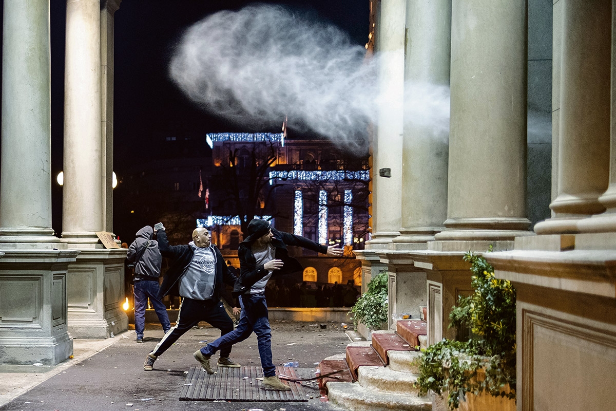 Demonstranten werfen Steine auf Polizeibeamte, die die Tür des Rathauses in Belgrad bewachen, 24. Dezember