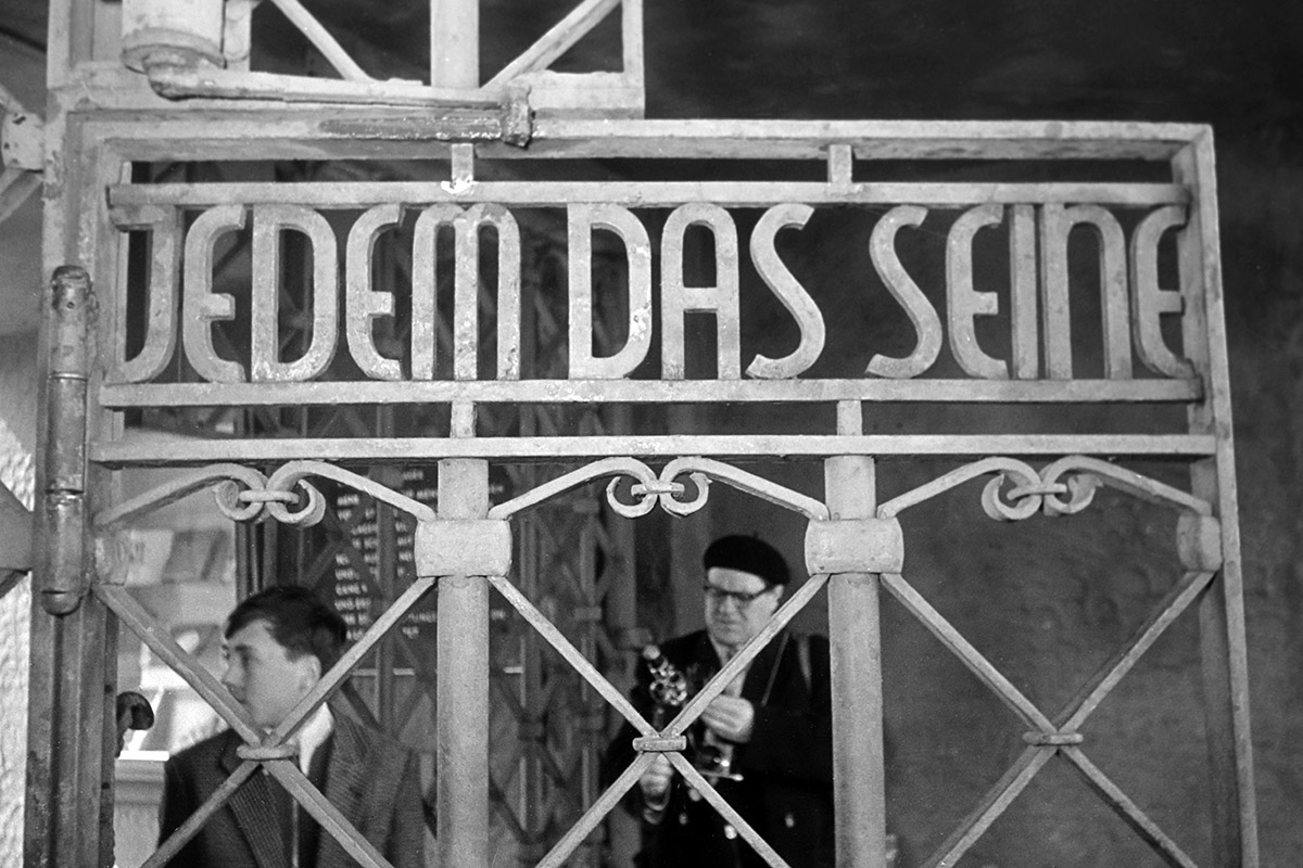 Besucher des KZ Buchenwald am Tor des Lagers mit dem Schriftzug »Jedem das Seine«, 1960