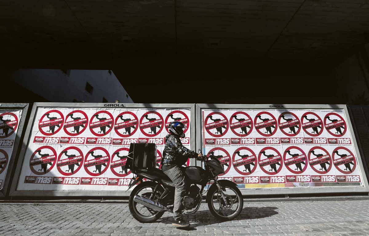 A motorcyclist drives his motorbike past posters on the streets that reads »No to the payment of the debt. Break with the IMF«, in Buenos Aires, Argentina February 22, 2020