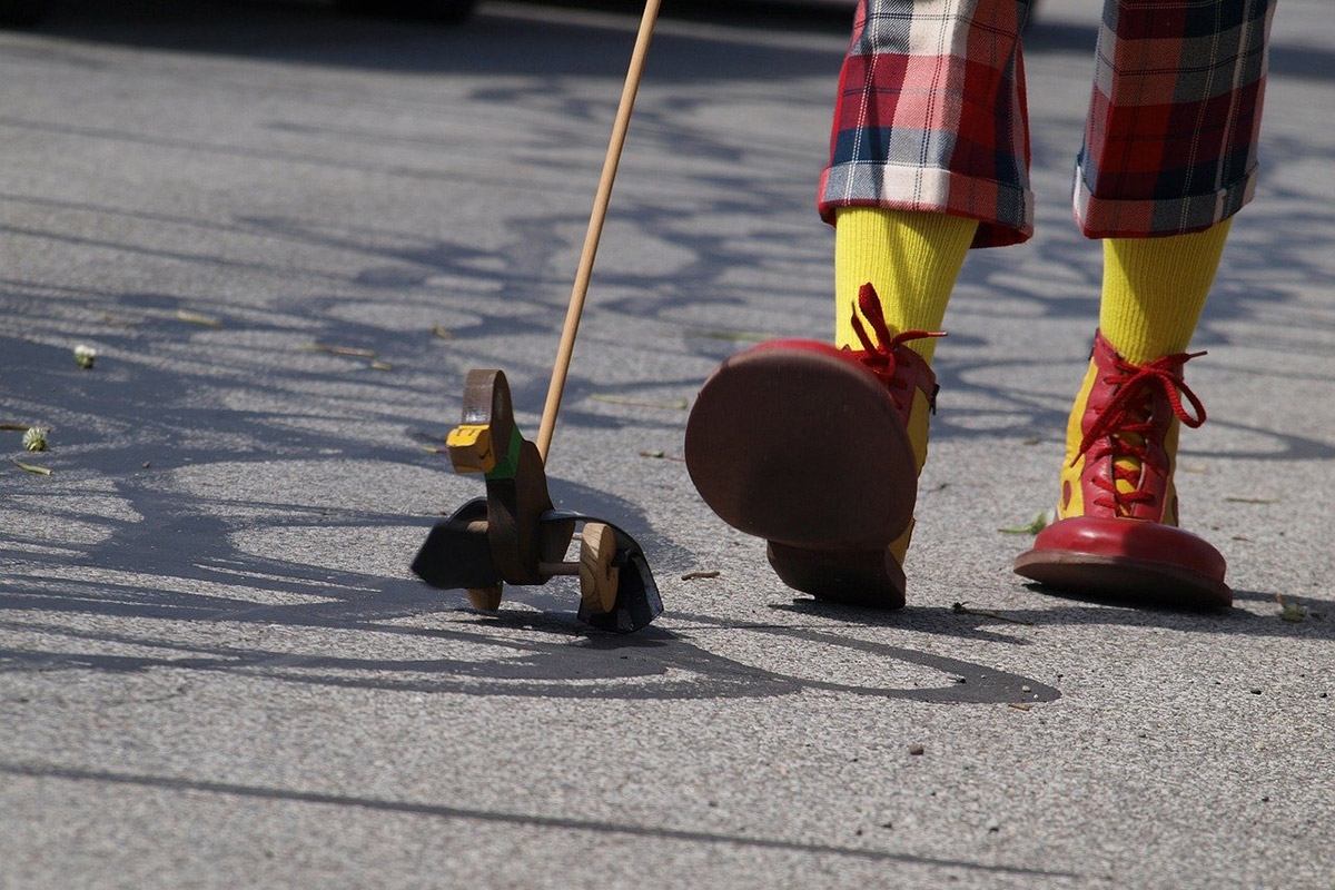 Schuhe und Hosenbeine eines Clowns mit Watschelente am Stock