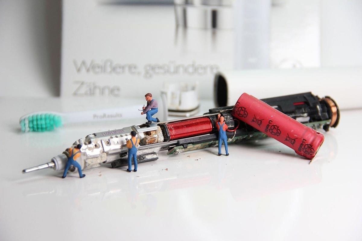 Miniaturfiguren reparieren eine elektronische Zahnbürste