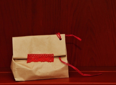 Ein profisorisch in eine Tüte mit rotem Faden und Klebeband verpacktes Geschenk