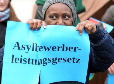 Eine Frau zerreißt symbolisch das Asylbewerberleistungsgesetz