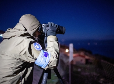 Person in Frontexuniform mit Fernglas