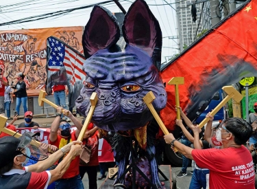 Teilnehmer einer 1. Mai-Demonstration in Quezon-Stadt schlagen auf ein Fabelwesen ein, das den Präsidenten Duterte darstellt