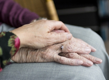 Eine Hand liegt auf Händen einer älteren Person