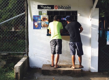 Zwei Personen stehen an einem Kiosk in El Zonte an dem nach Beschilderung mit Bitcoin gezahlt werden kann
