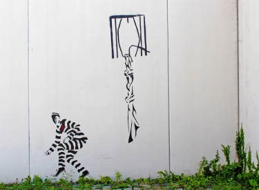 Graffiti Knastmauer auf einer Knastmauer: Fenster mit geknotetem Laken und Person in Knastkleidung, die wegschleicht