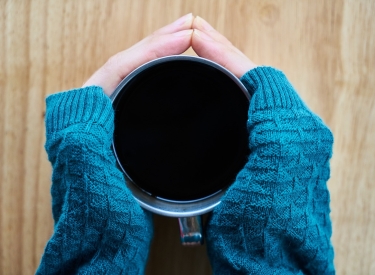 Zwei Hände umfassen eine Kaffeetasse