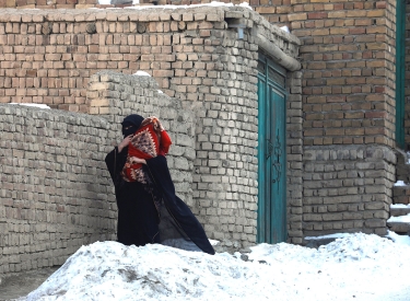 Eine Frau in schwarzem Gewand vor einer Backsteinmauer