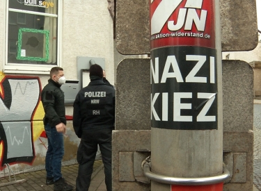 Polizisten stehen vor der Gaststätte "Bull's Eye". An einem Pfahl ist ein Aufkleber mit der Aufschrift Nazi Kiez zu sehen.