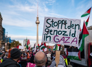 Einer der Teilnehmer haelt ein Schild auf dem steht: "Stoppt den Genozid in Gaza".